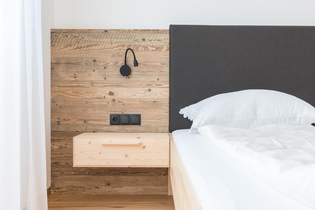 1 dormitorio con cama blanca y pared de madera en Mesnerhof Chalet en Bressanone