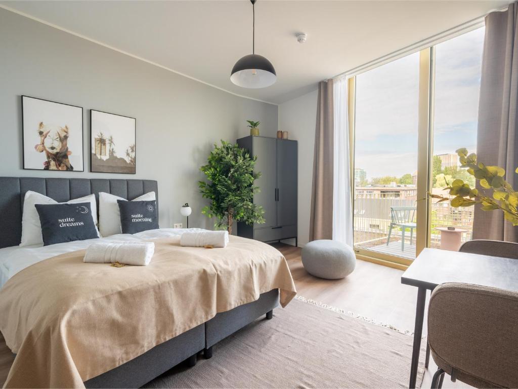 a bedroom with a bed and a table and a window at Limehome Eindhoven Gashouder in Eindhoven