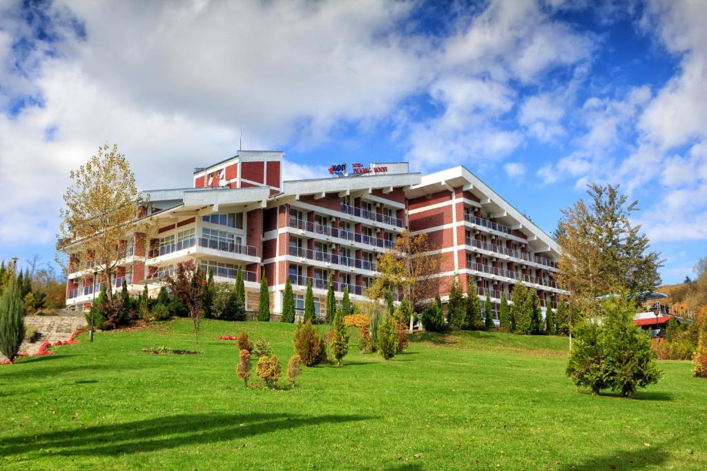 een groot rood gebouw op een groen veld bij Relax Coop Hotel in Voneshta Voda