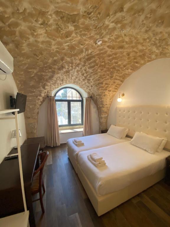 um quarto com 2 camas e uma parede de pedra em Petrakis Inn em Jerusalém