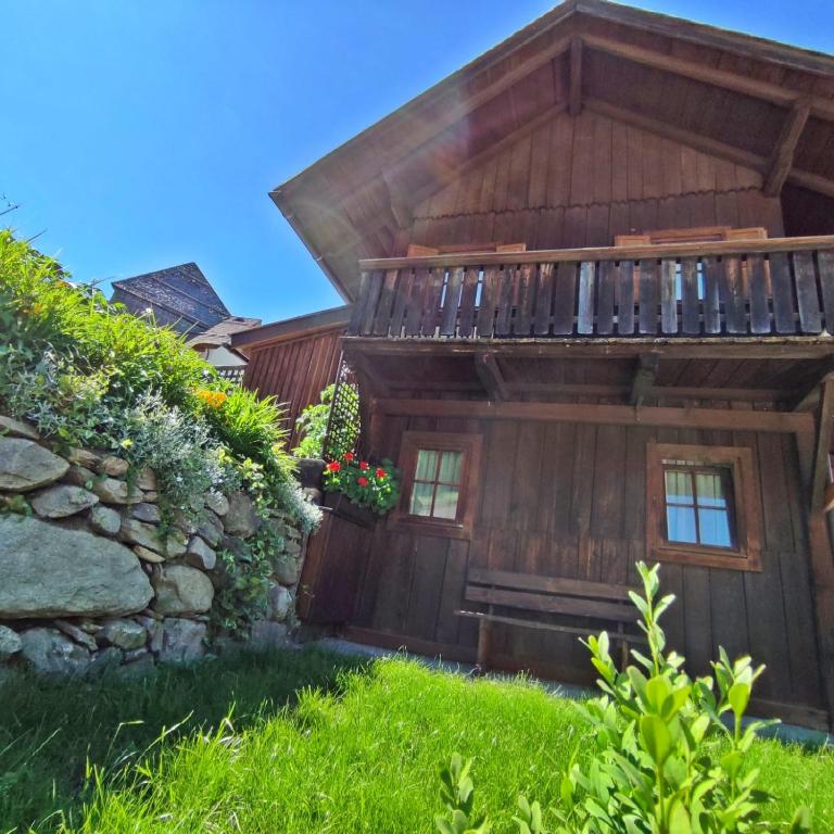 a wooden house with a balcony and a stone wall at Chalet Maurer in Cadipietra