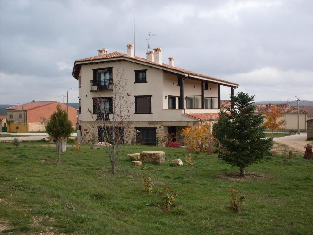 a house in a field with a tree in front of it at Hotel Valdelinares (Soria) in Valdelinares