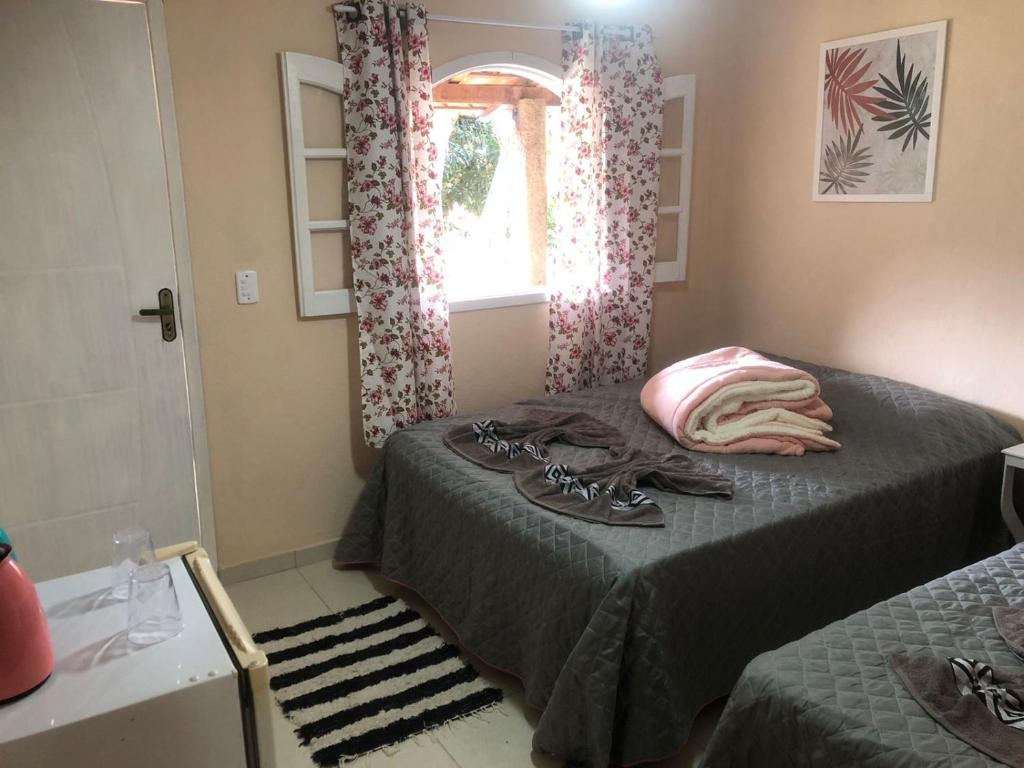 a small bedroom with two beds and a window at Pousada Recanto dos Arcos in Conservatória