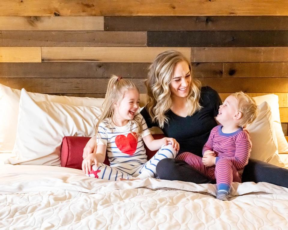 a woman and two children sitting on a bed at Sawtelle Mountain Resort in Island Park