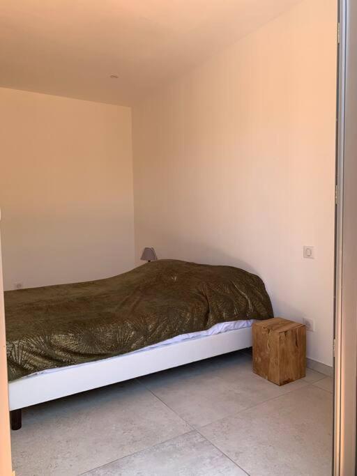 a bedroom with a bed and a wooden stool at Maison neuve avec piscine in Corbara