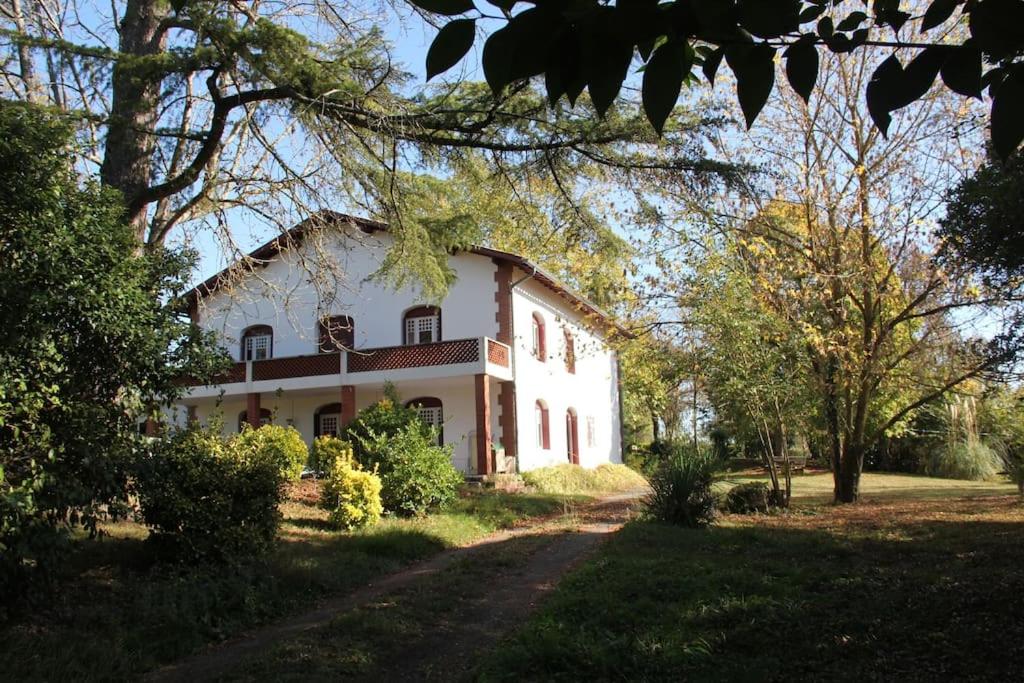 duży biały dom z drzewami przed nim w obiekcie maison de campagne avec grand lac et park arboré 