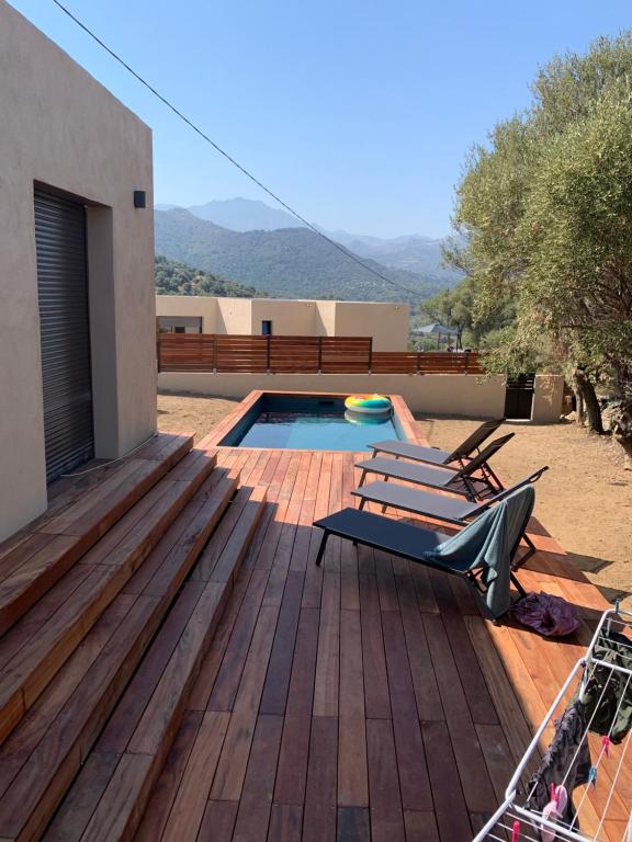 a deck with a bench and a swimming pool at Maison neuve avec piscine in Corbara