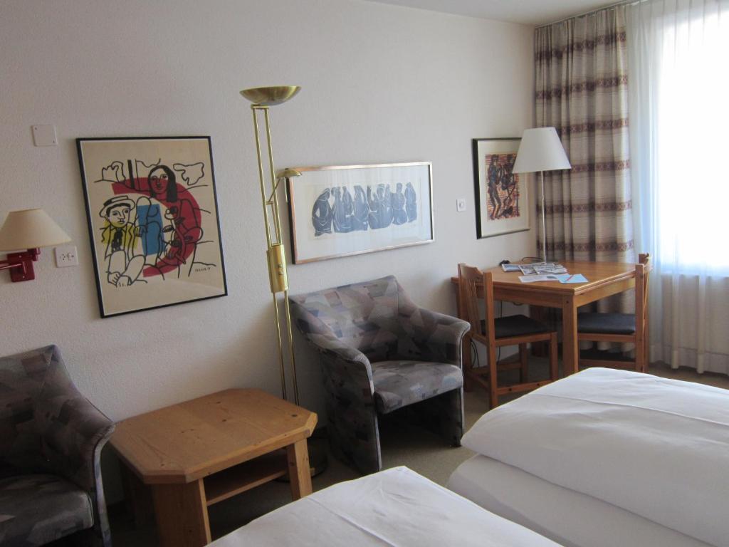 um quarto de hotel com uma cama, uma cadeira e uma mesa em Studio im Hotel Des Alpes em Flims