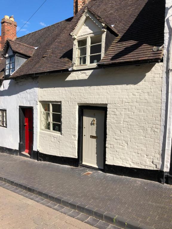 a white house with a red door on a street at Little Gem on Bridgnorth's Cartway. River Views in Bridgnorth