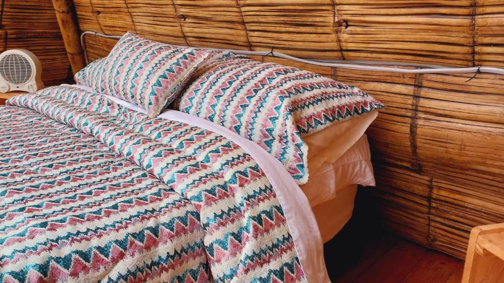 a bed with a colorful blanket and a pillow at Alas Glamping La Cima in Guatavita