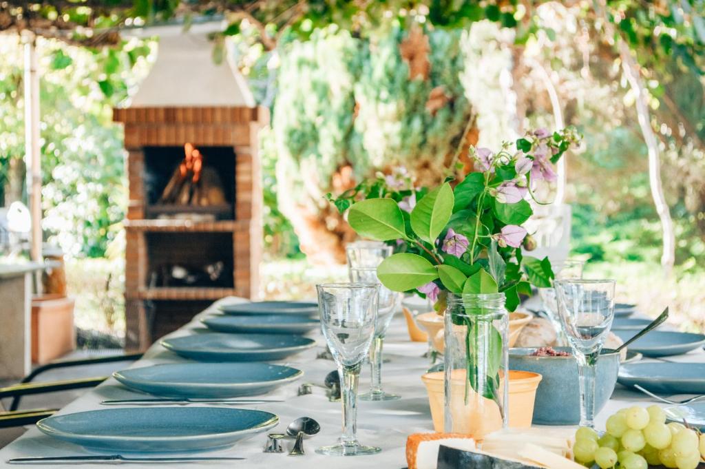 uma mesa com pratos e copos e um vaso de flores em Just Like Home - Casa do Sobreiro Velho em Cerveira em Vila Nova de Cerveira