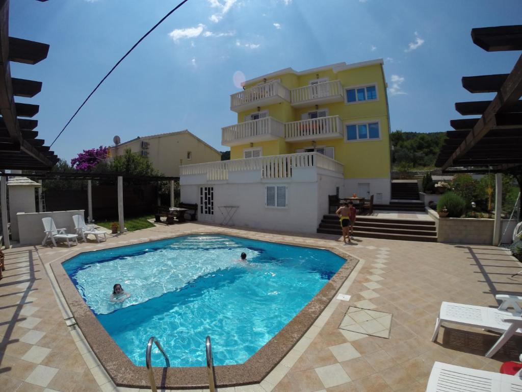 a villa with a swimming pool in front of a building at Apartments Romana in Slatine