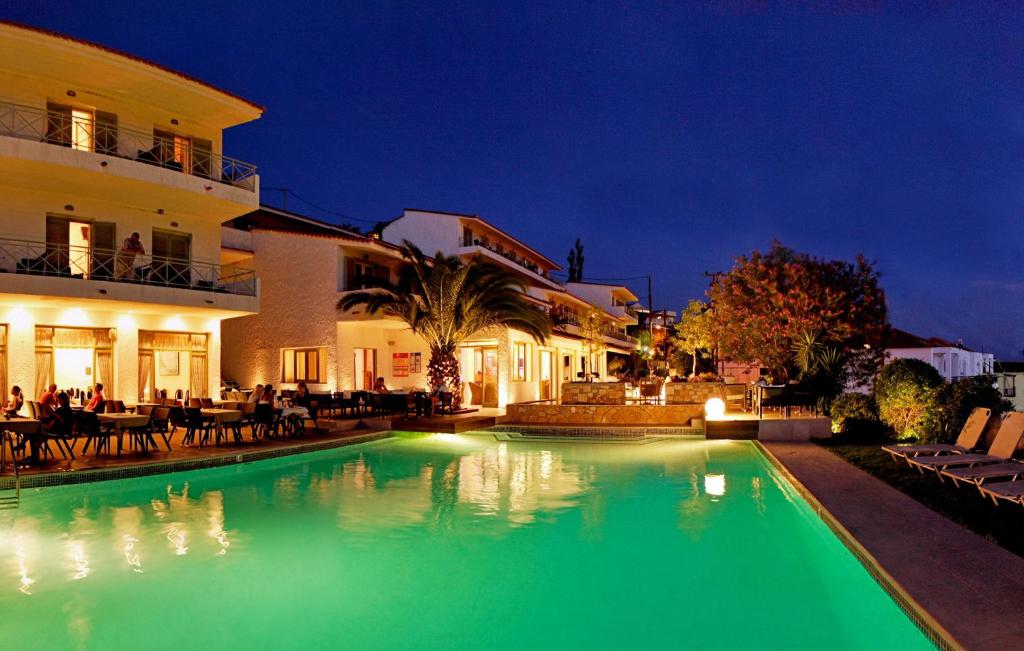 a swimming pool with green lighting in front of a building at Sandy Bay Hotel in Plomari