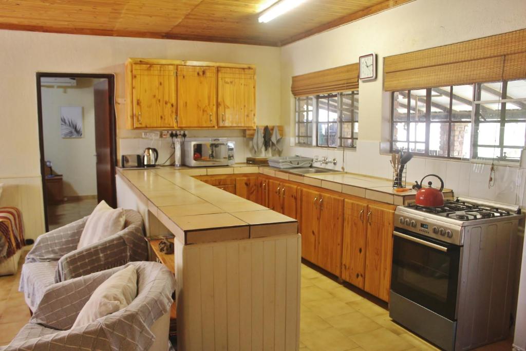 a kitchen with wooden cabinets and a stove top oven at Nature Rest in Marloth Park