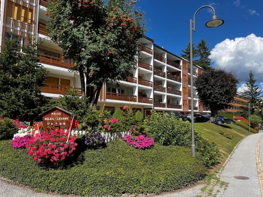 a garden with flowers in front of a building at Cozy central apartment at a special price! in Crans-Montana