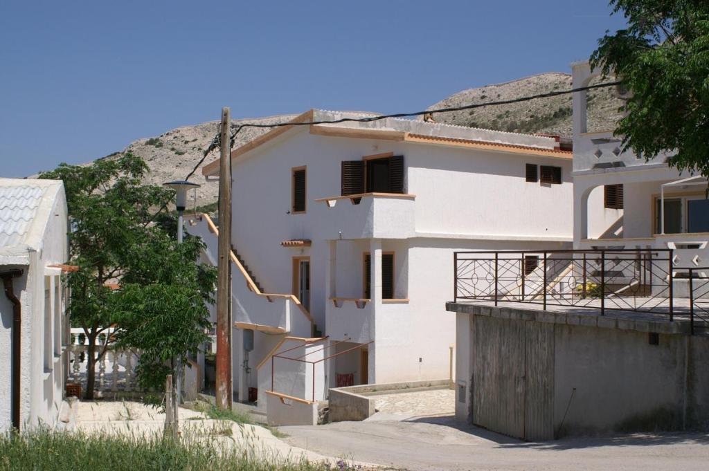 a white building with stairs in front of a hill at Apartment Metajna 525d in Zubovići