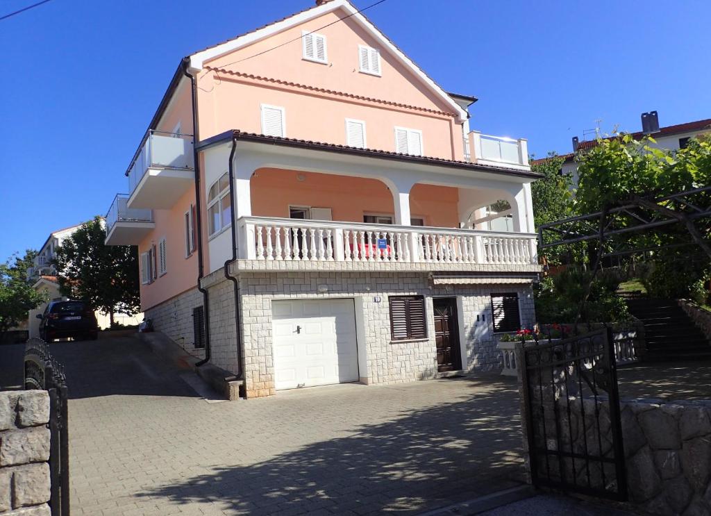 a large pink house with a balcony on a street at Apartments with parking space Vantacici, Krk - 427 in Malinska