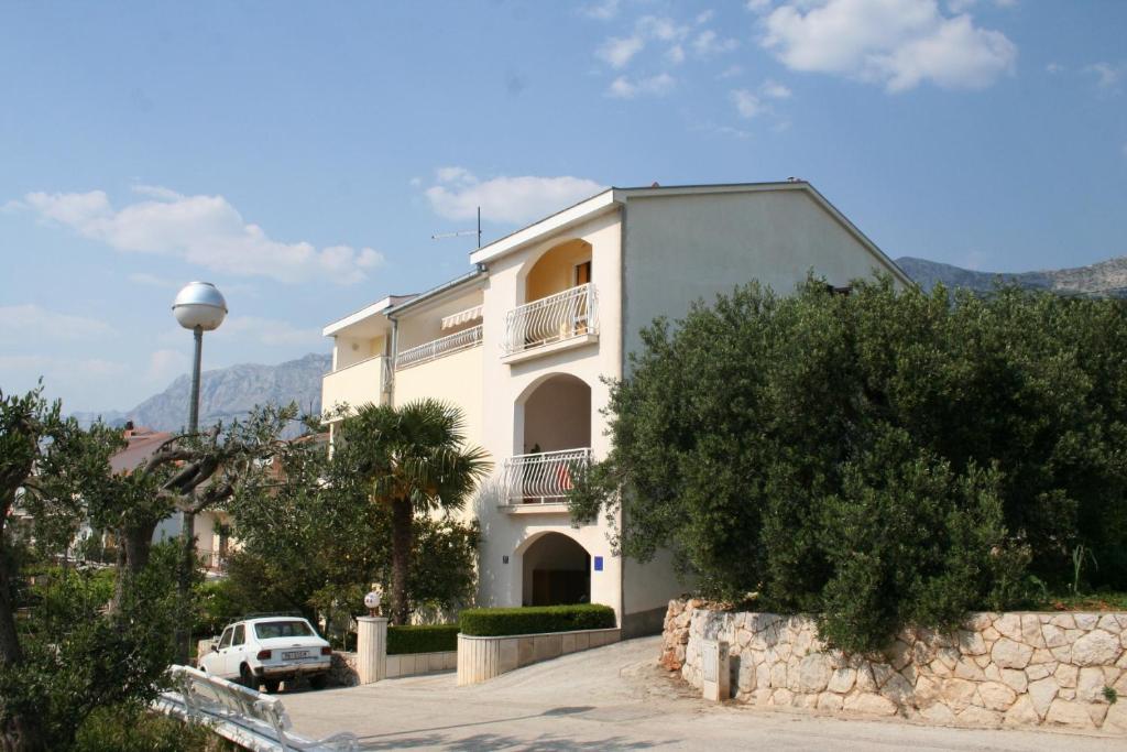 ein weißes Haus mit einem davor geparkten Auto in der Unterkunft Apartment Podgora 518a in Podgora