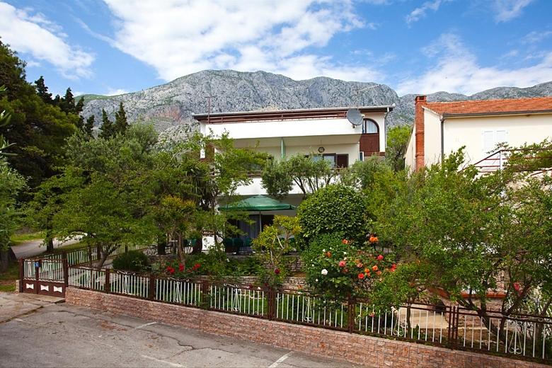 budynek z ogrodzeniem, drzewami i górą w obiekcie Apartments and rooms by the sea Zivogosce - Blato, Makarska - 521 w mieście Igrane