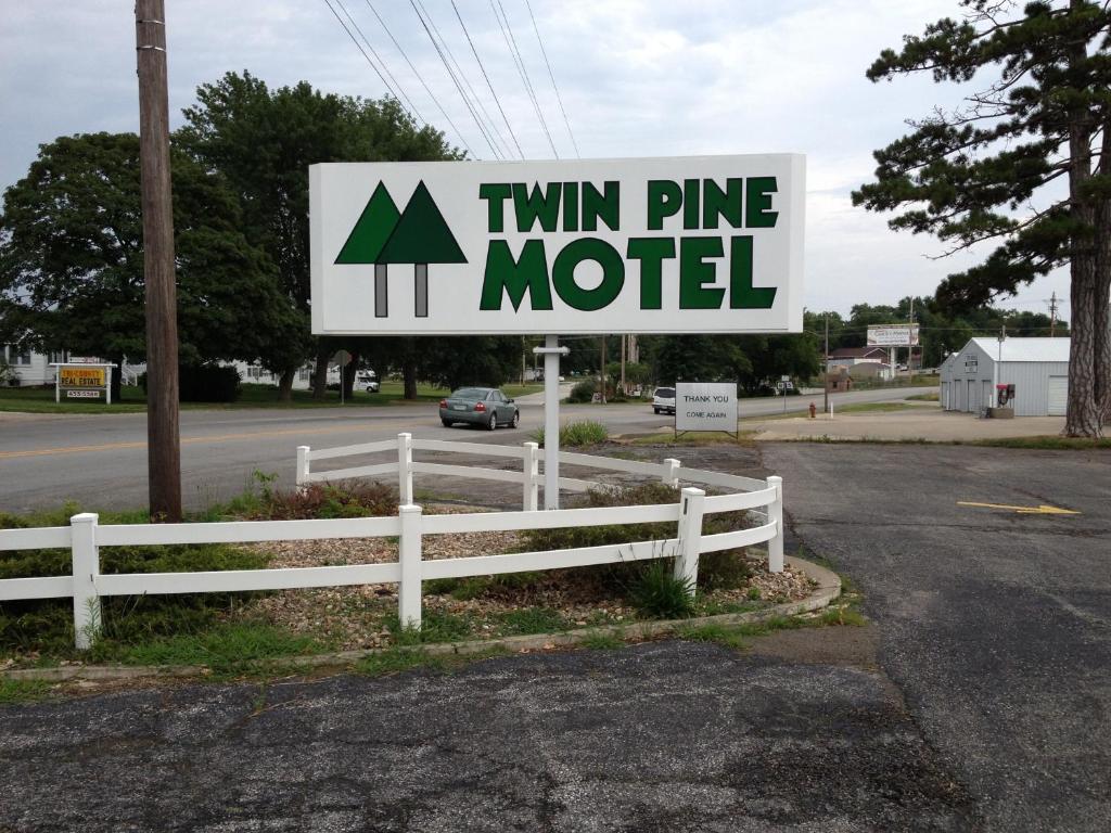 una señal para un motel de pino gemelo junto a una valla en Twin Pine Motel, en Tipton