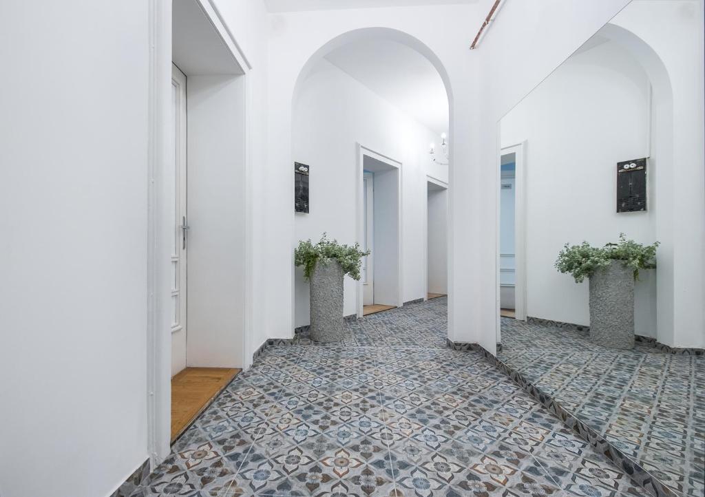 un couloir vide avec des murs blancs et des colonnes blanches avec des plantes en pot dans l'établissement Apartamenty Piłsudskiego, à Gliwice