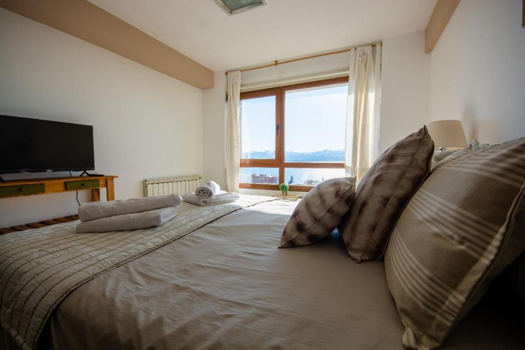 a bedroom with a large bed with pillows and a window at Tu Apart En Bariloche 34 in San Carlos de Bariloche