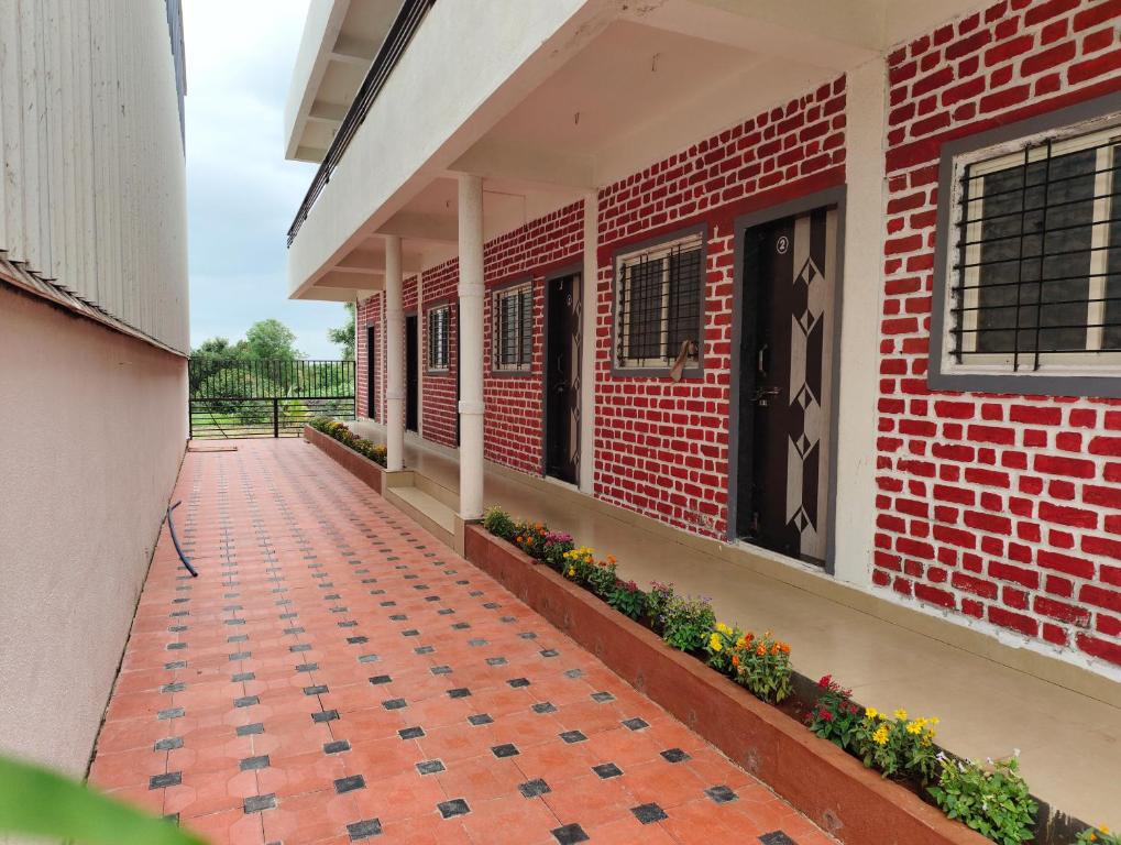 um edifício de tijolos com um passadiço e flores nele em Fulgulab Lawns and Home Stay em Junnar