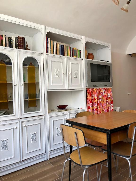 uma sala de jantar com armários brancos e uma mesa e cadeiras em La Taverna del Ricetto em Candelo