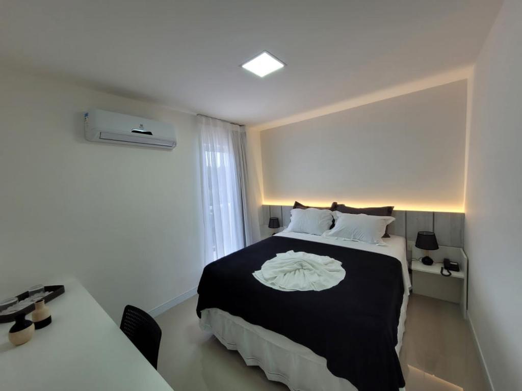 a bedroom with a black and white bed and a desk at Edifício Royale flat 230 in Cabo Frio