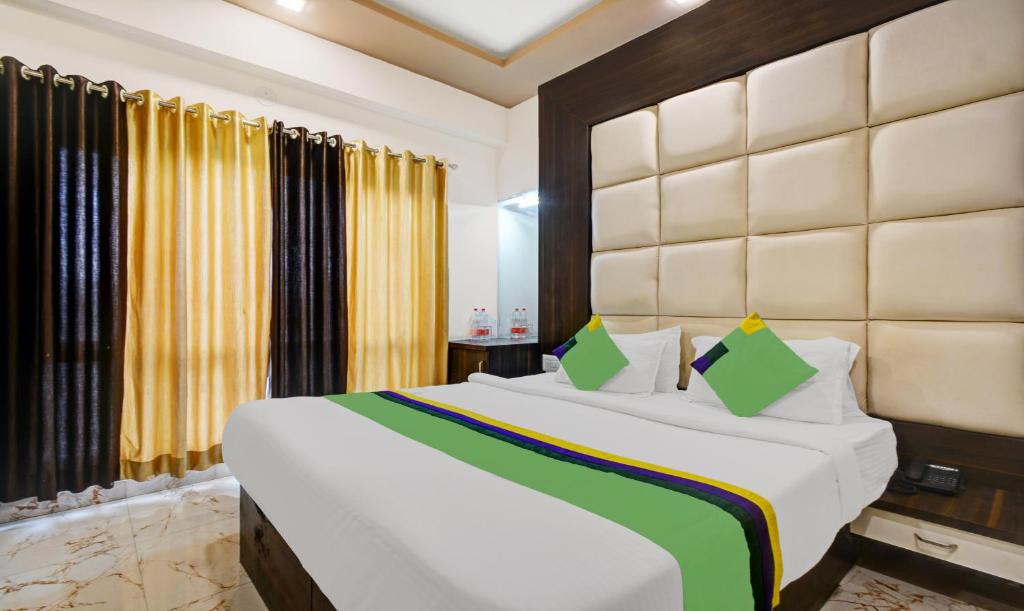 a bedroom with a large white bed with yellow curtains at Treebo Trend Mangal Residency in Udaipur