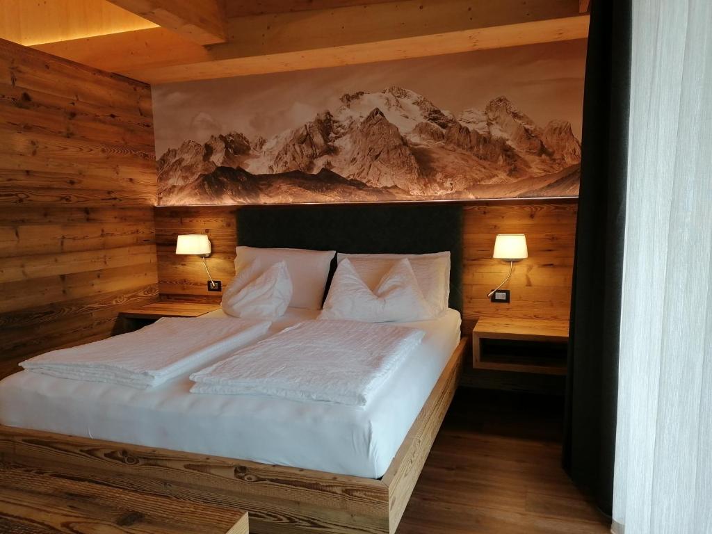 a bedroom with a white bed with two night stands at DOLOMITES B&B - Suites, Apartments and SPA in Tesero