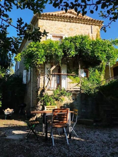 une table et une chaise devant le bâtiment dans l'établissement Elégante maison des Baronnies avec grand jardin, à Les Isnières