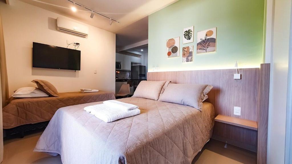 a bedroom with two beds and a flat screen tv at Nova aliança 56 -wifi -estacionamento -3 hóspedes in Ribeirão Preto