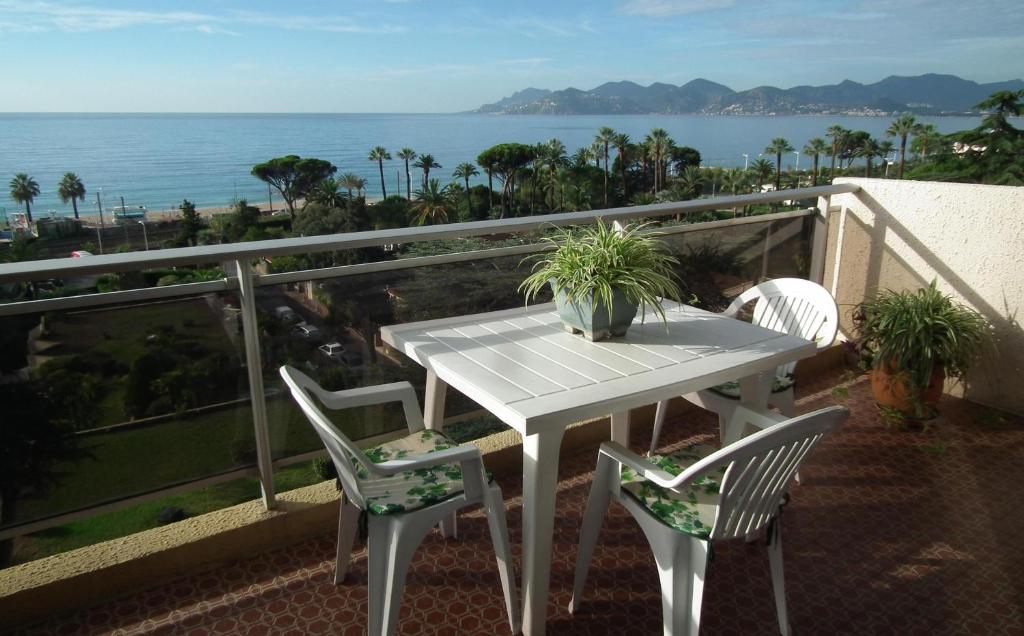 uma mesa branca e cadeiras numa varanda com o oceano em Apartment Montmorency em Cannes