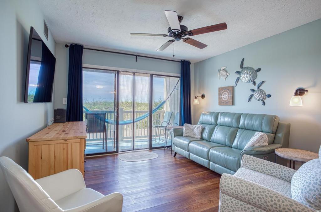 a living room with a couch and a balcony at BEAUTIFUL BEACHFRONT-Oceanfront First Floor 2BR 2BA Condo in Cherry Grove, North Myrtle Beach! RENOVATED with a Fully Equipped Kitchen, 3 Separate Beds, Pool, Private Patio & Steps to the Sand! in Myrtle Beach