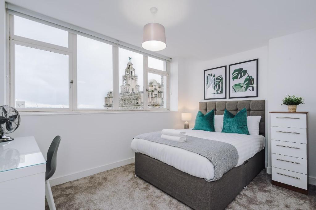 a white bedroom with a large bed with blue pillows at Host & Stay - Waterfront Penthouse in Liverpool