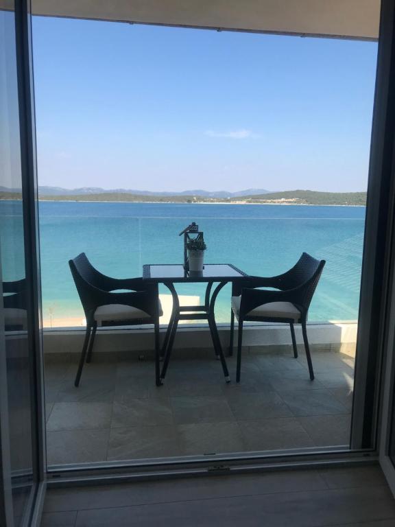 een tafel met twee stoelen en uitzicht op de oceaan bij Villa Danica Murter in Betina
