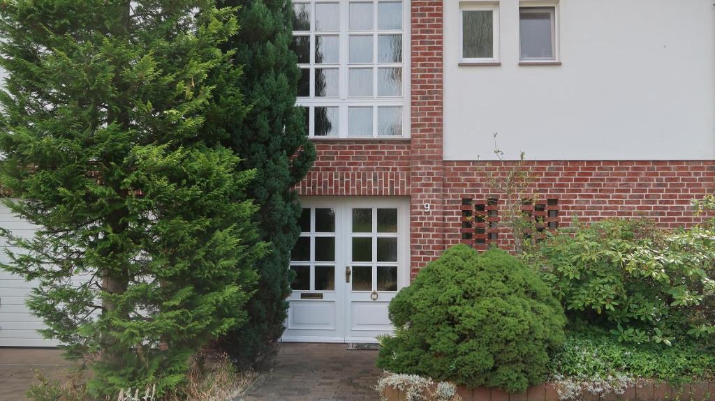 una casa de ladrillo con una puerta blanca y arbustos en Ferienwohnung Walter - Friedrichroda, en Friedrichroda