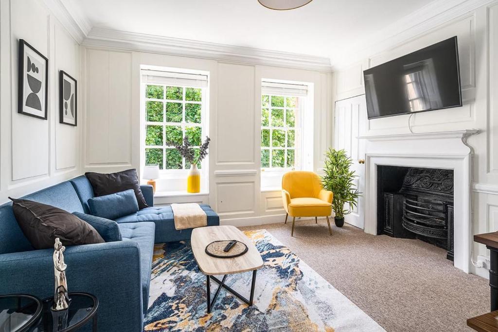 a living room with a blue couch and a fireplace at Stunning 3 Bedroom Period City Centre Apartment in Bath