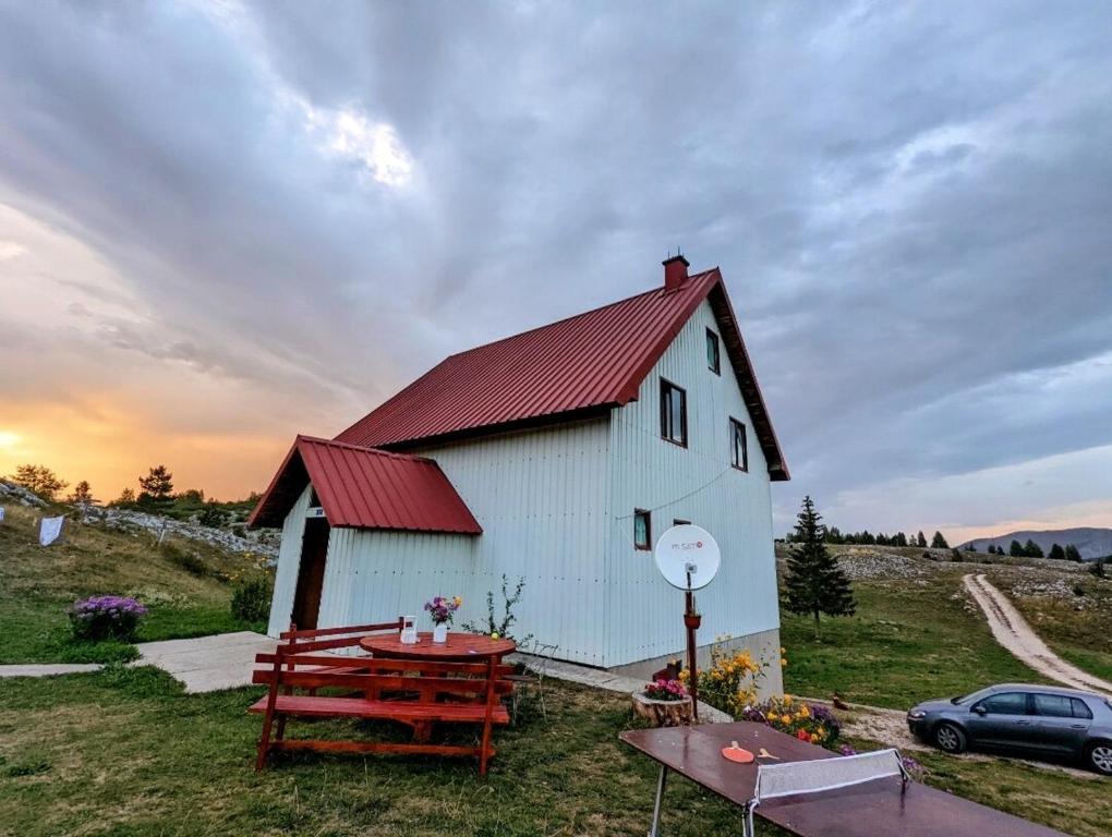 a white building with a red roof and a picnic table at Apartmani Laušević in Žabljak