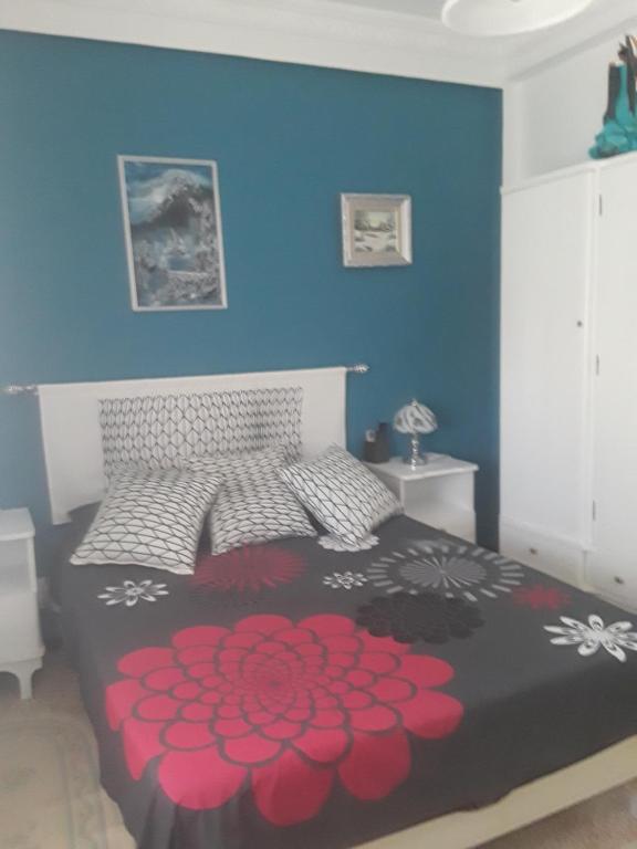 una camera da letto con un grande letto con fiori rossi di Bel Appartement Kouba Centre a Alger