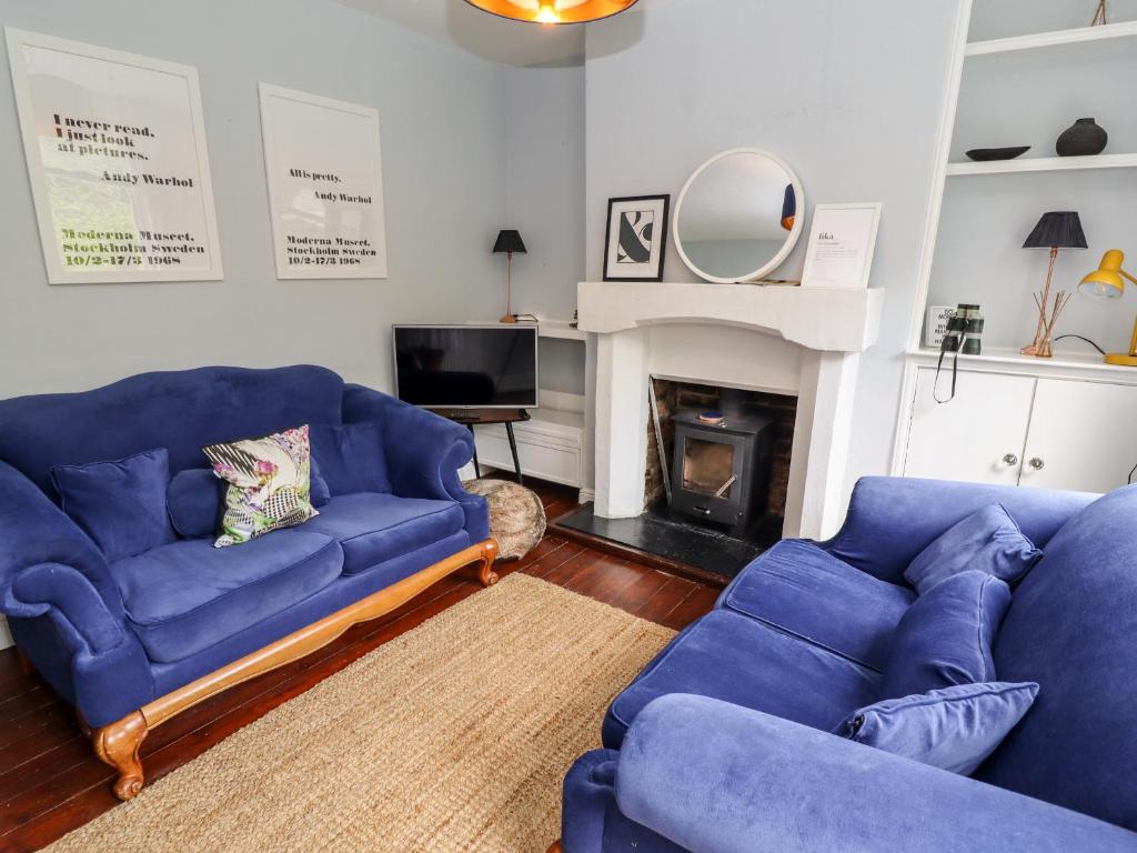 ein Wohnzimmer mit 2 blauen Sofas und einem Kamin in der Unterkunft Lime Cottage in Matlock