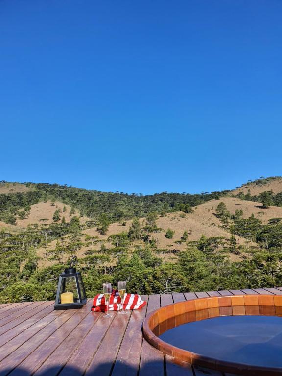 eine Holzterrasse mit einem Pool und einem Hügel in der Unterkunft locanda cecchini in Campos do Jordão