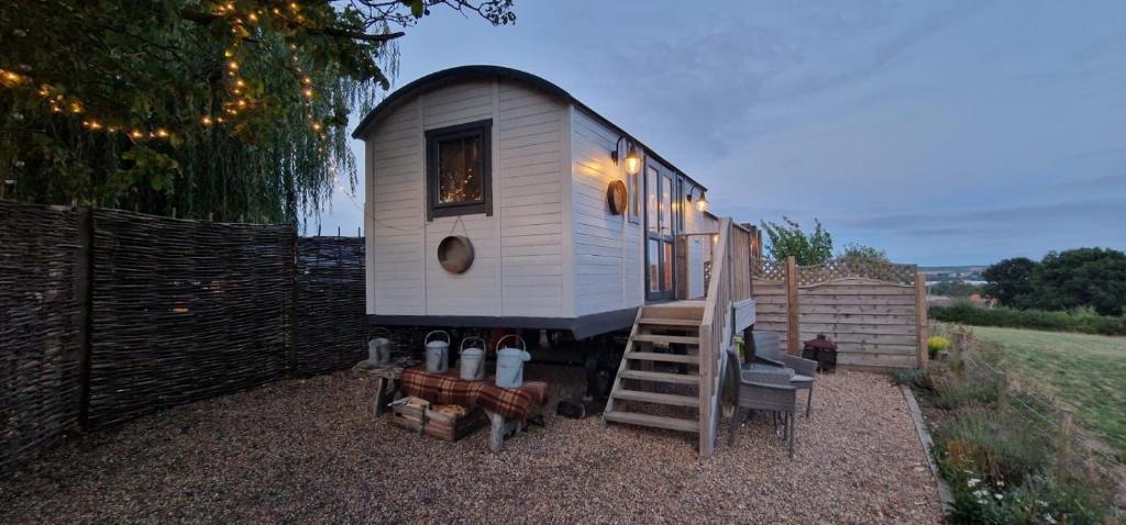 a tiny house with a staircase and a fence at The cosy hut in Faversham
