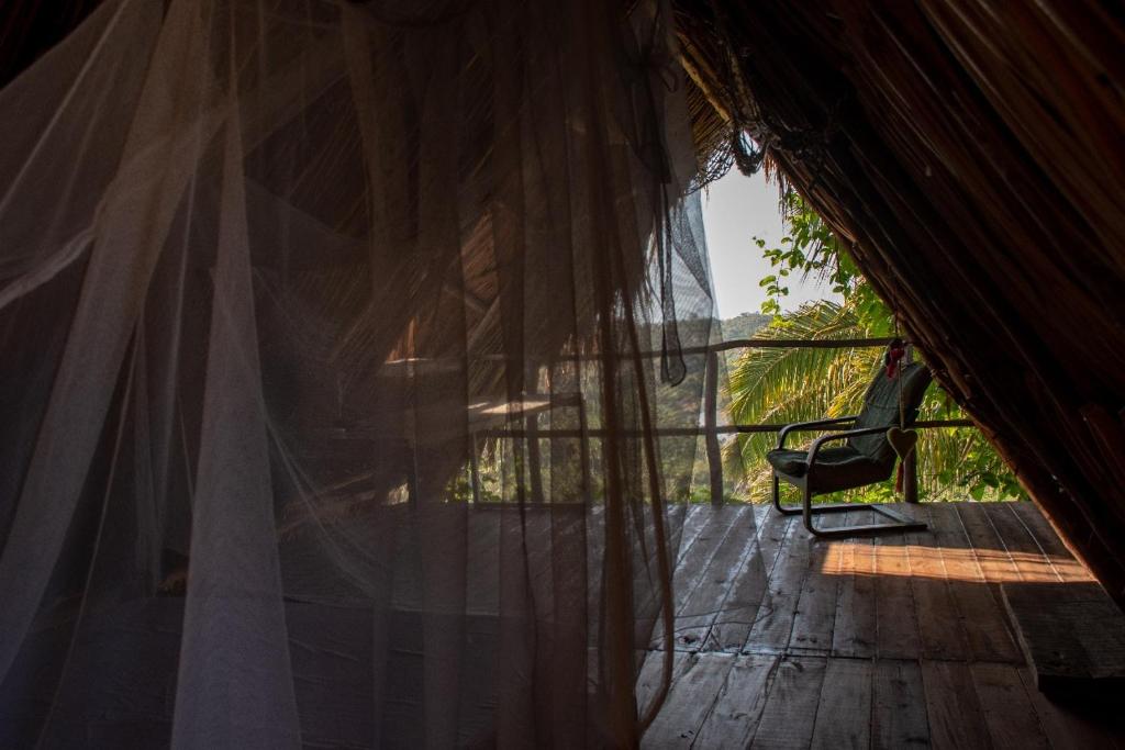 Zimmer mit einem Fenster und einem Stuhl auf einer Terrasse in der Unterkunft Elemental lodge in Santa Marta