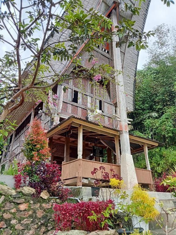 an old house with flowers in front of it at NUANSA HOMESTAY Authentic&Hospitality in Rantepao