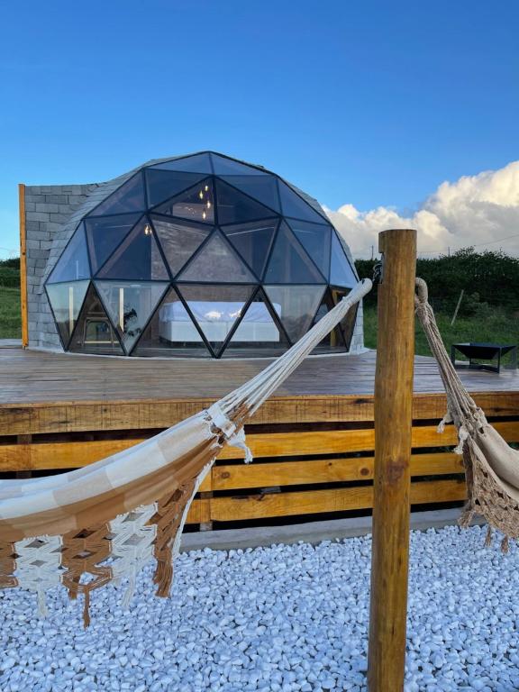 a glass house with a hammock on a wooden deck at Domo do Matto in Garanhuns