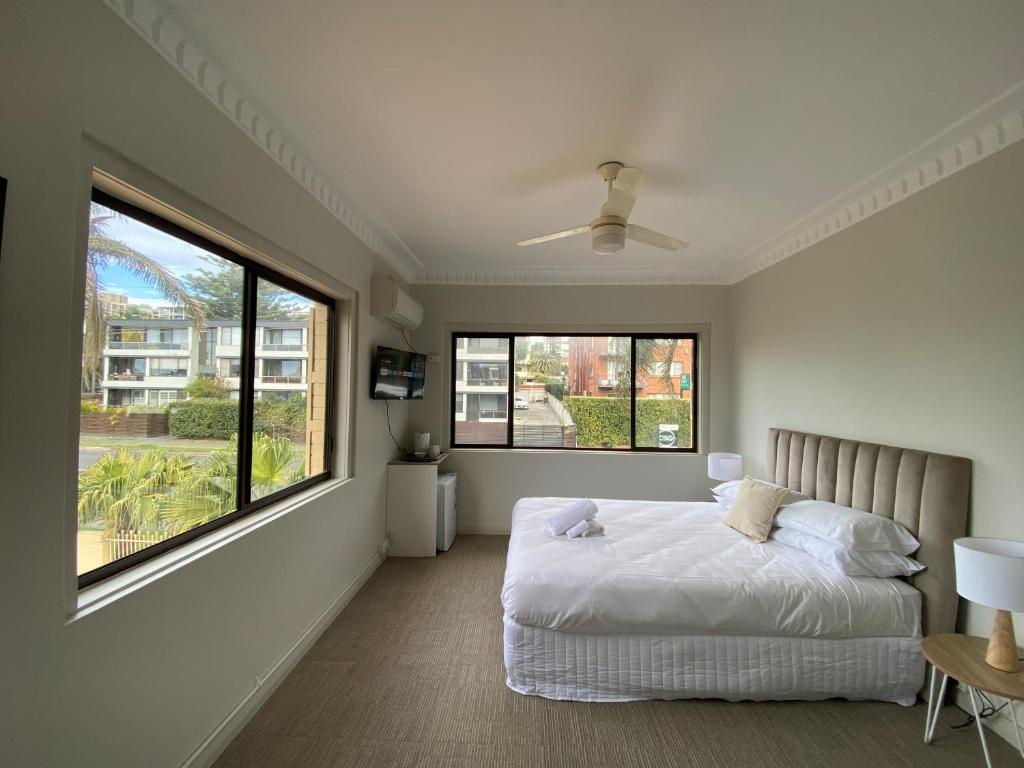 um quarto com uma cama e uma grande janela em Normandie Wollongong em Wollongong