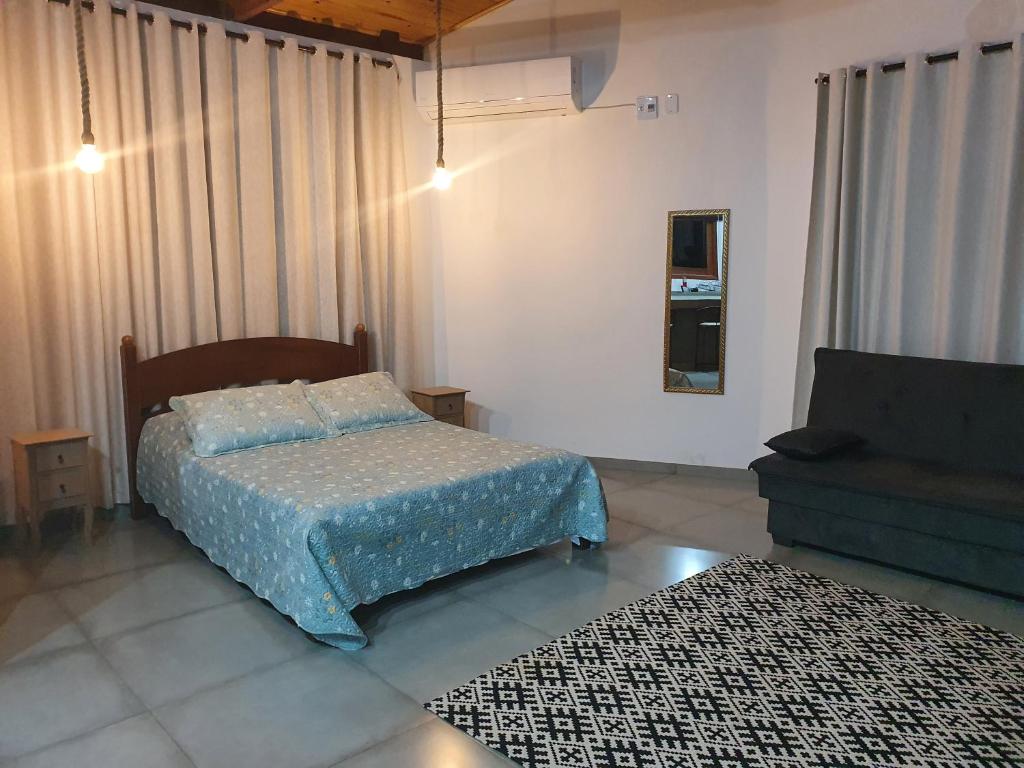 een slaapkamer met een bed en een bank bij Loft Pé na Serra in Cachoeiras de Macacu