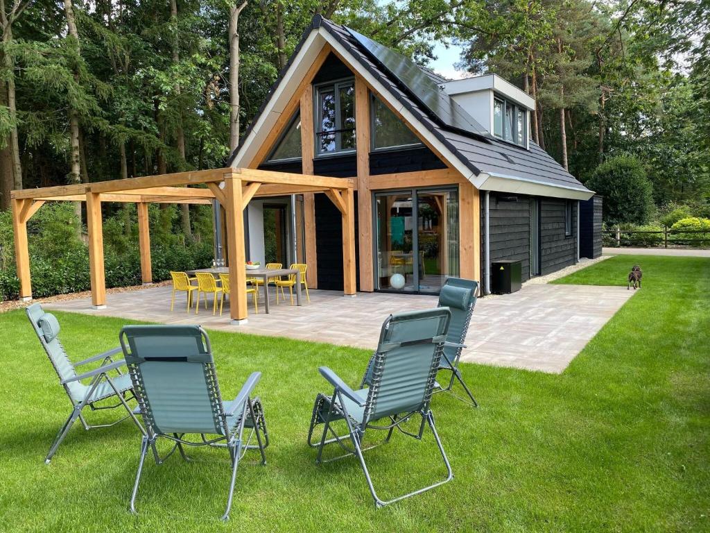 un groupe de chaises assises sur l'herbe devant une maison dans l'établissement Modern holiday home in Lochem with private garden, à Lochem